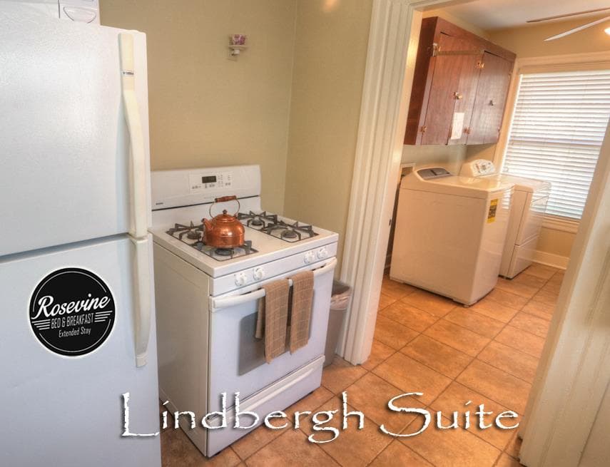 The downstairs Lindbergh Suite kitchen has a white fridge, white stove and access to a shared laundry room with white washer and dryer