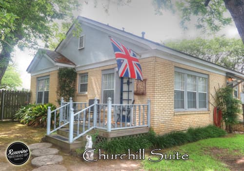 The exterior of the Churchill Suite is yellow brick and the entrance has a wood deck with several stairs and a blue door with glass windows