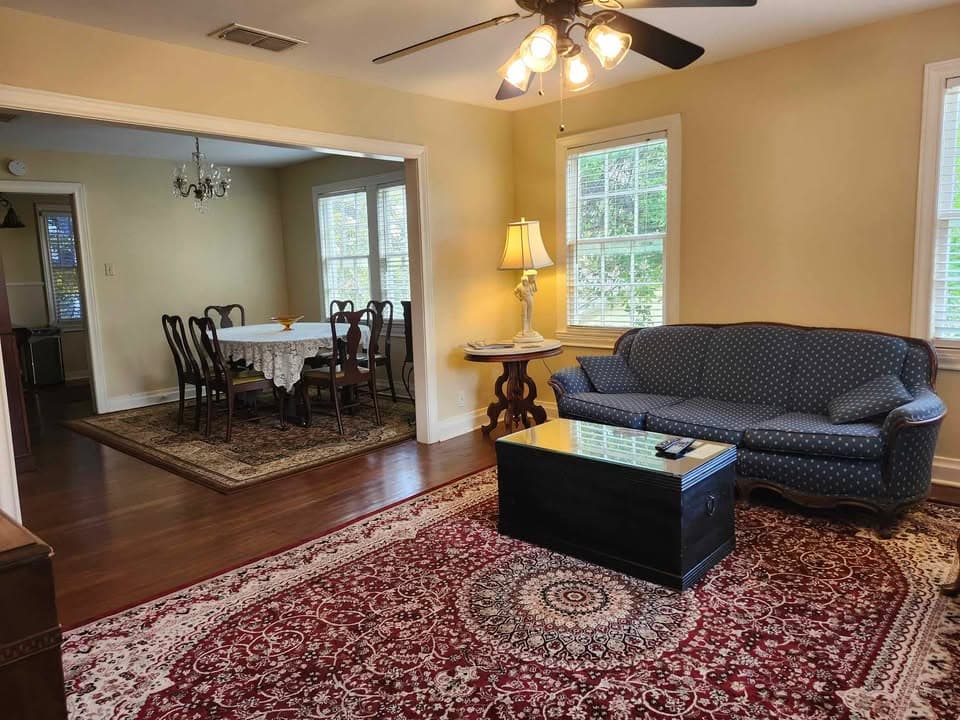 living room with black sofa and dining room in background.
