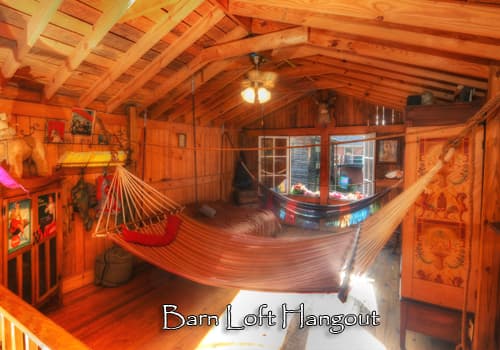 The second floor of the barn game room has wood walls, wood floors and two hammocks