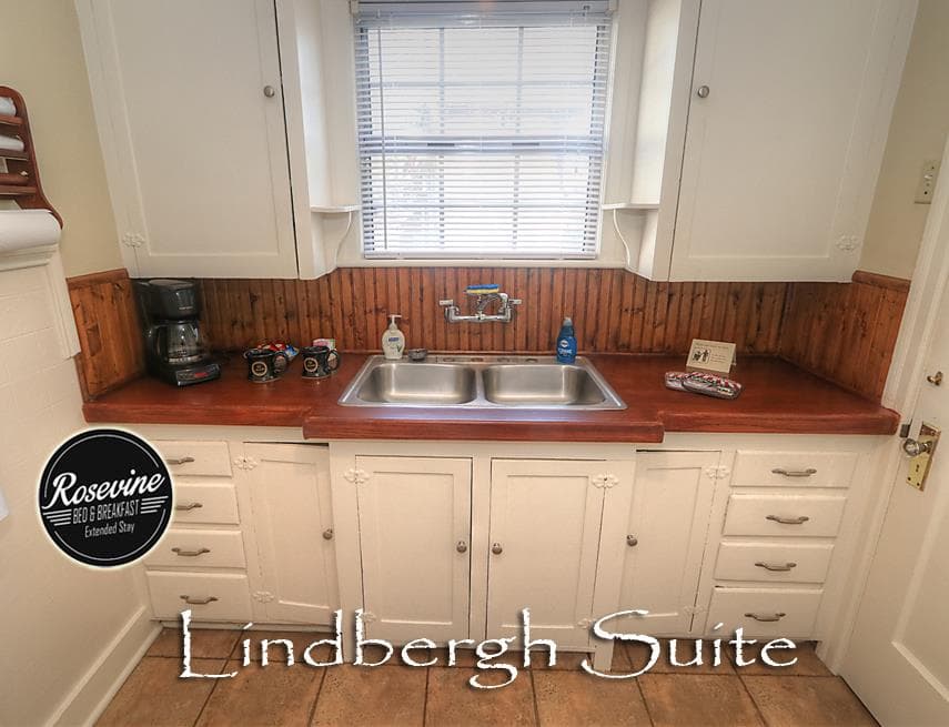 The downstairs Lindbergh Suite Kitchen has white cabinets with wood countertops and wood backsplash