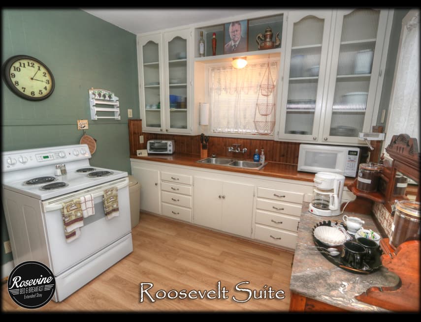 The Roosevelt Kitchen has white cabinets, wood countertops, white oven and table coffee bar
