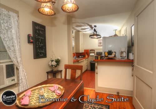 The upstairs Bonnie & Clyde Dining Room and Kitchen combo feature a brown wood table with two chairs, an oven, microwave and fridge