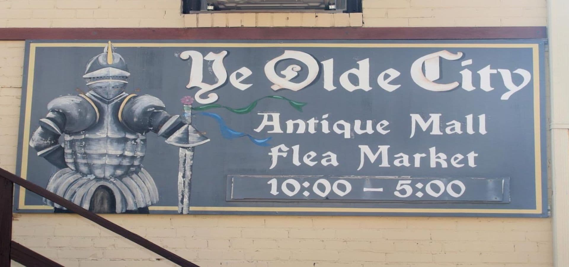Sign for "Ye Olde City Antique Mall and Flea Market" featuring a knight in armor, with operating hours from 10:00 to 5:00.