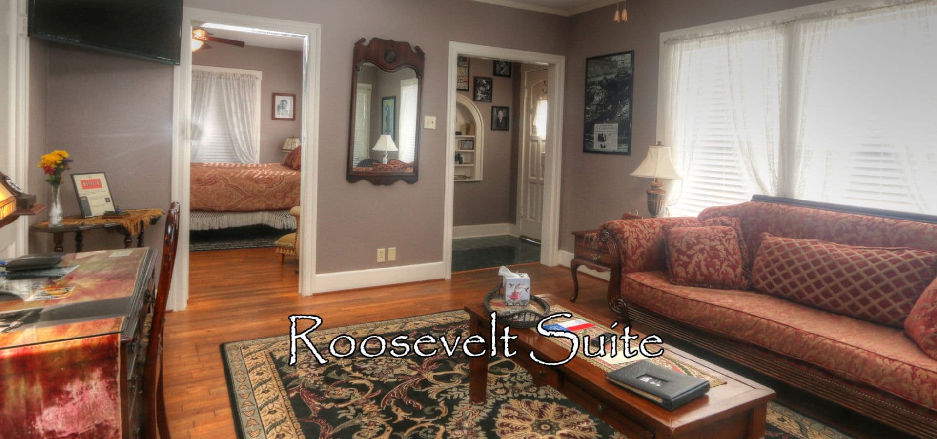 Cozy living area of the Roosevelt Suite featuring a seating area, a desk, and natural light from large windows.