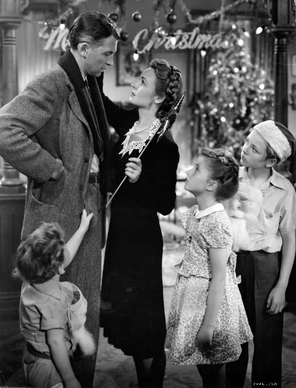 Black and white image of a scene from the classic movie Its a wonderful Life-depicts George Bailey and his wife and 3 children on Christmas