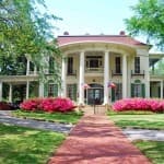 picture of the front façade of the Goodman-Legrande house, an 1800's home and museum with a red brick walkway leading to the house
