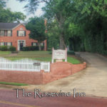 The Exterior of the Rosevine Inn Bed and Breakfast. A two story brick building with a brick clock towner and american flags