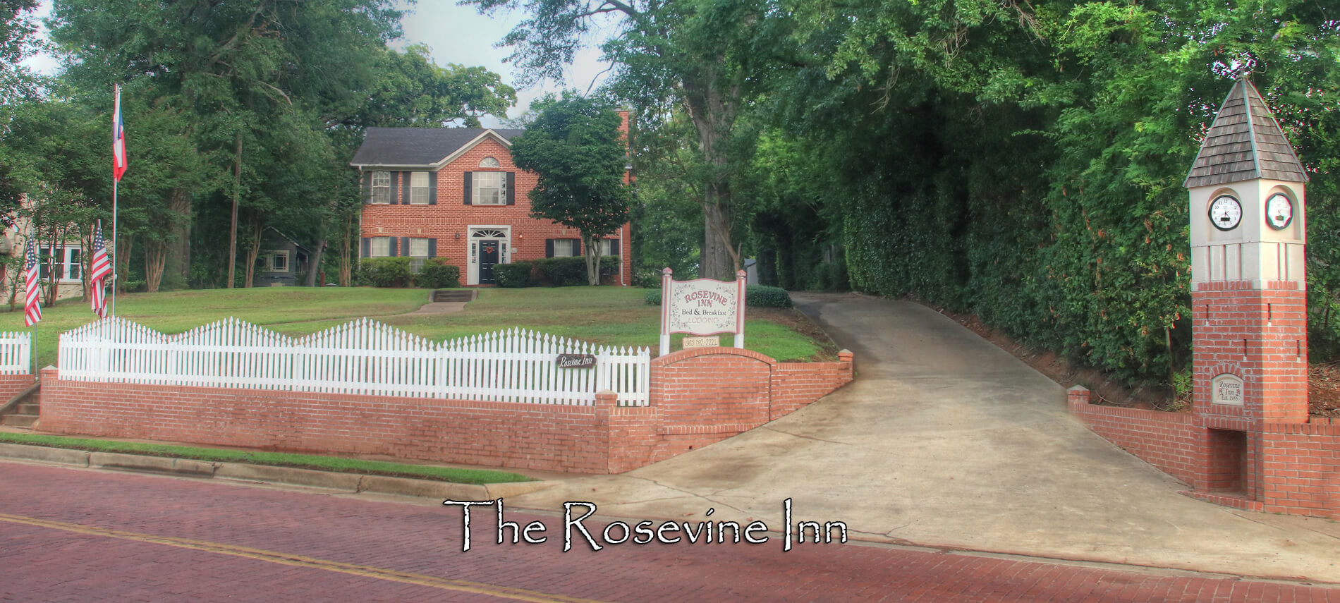 The Exterior of the Rosevine Inn Bed and Breakfast. A two story brick building with a brick clock towner and american flags