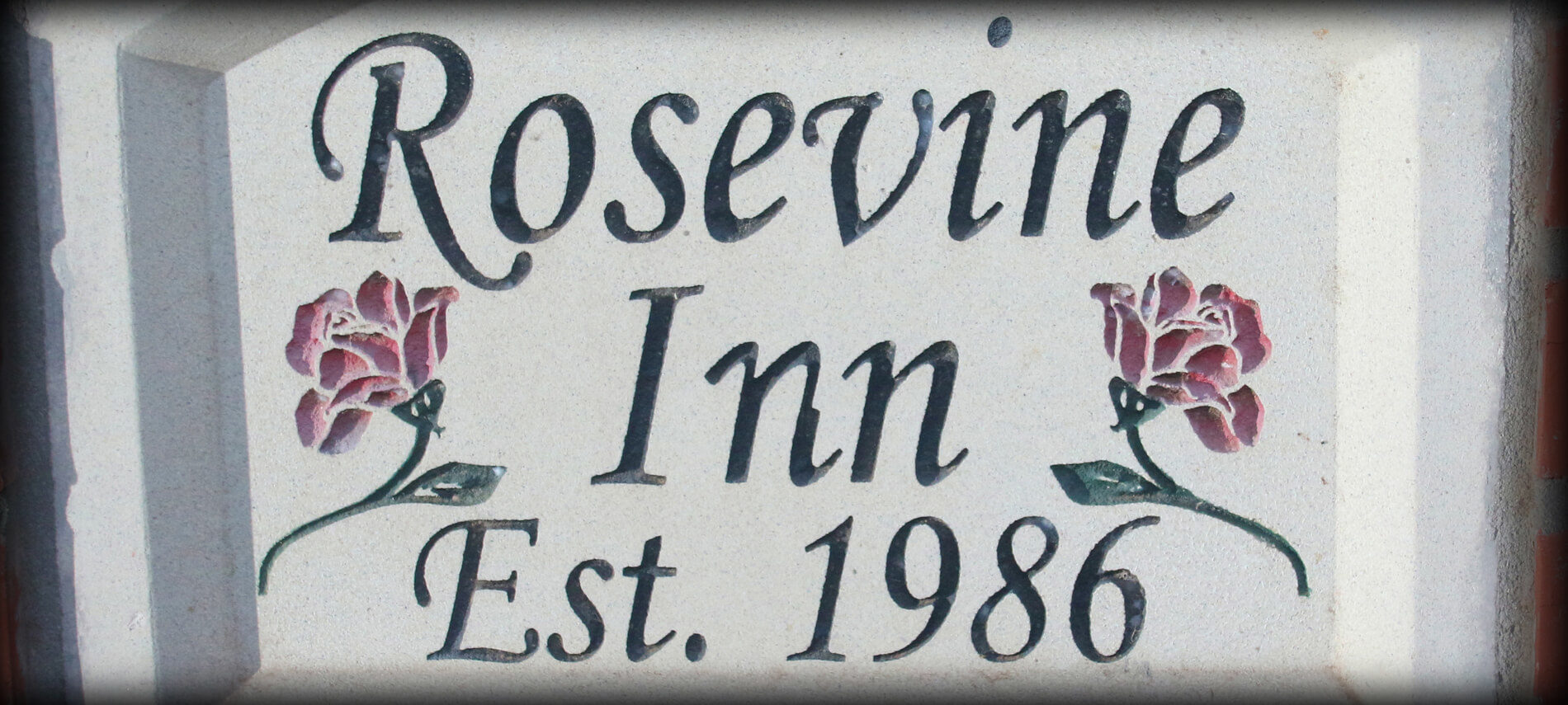 Rosevine Inn Creme Plaque that says Rosevine Inn established 1986 with 2 red roses etched on either side