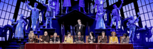 several people sitting at along table Lurch is standing up! The cast of the Addams Family in costume