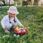 Cute little four year old girl enjoying Easter egg hunt in a public park