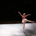 Ballerina on stage. She is on one toe with other leg out to the side