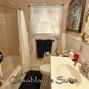 Bathroom with Navy Blue Towels, a comomde, sink and tub with shower