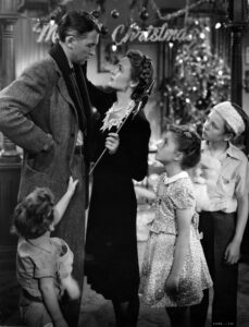 Black and white image of a scene from the classic movie Its a wonderful Life-depicts George Bailey and his wife and 3 children on Christmas