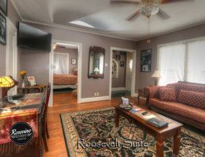 Red couch, rug, tv and writing desk