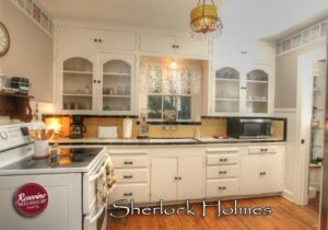 Sherlock Holmes Kitchen with white oven stove, white cabinets, kitchen sink, fridge and microwave