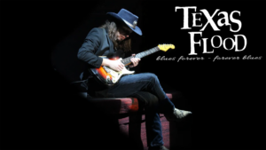 black background with man sitting on a stool with a guitar. He is wearing a cowboy hat, dark clothes and cowboy boots. The words Texas Flood-blues forever-forever blues.