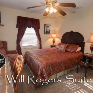 Highback bed covered in red comforter with gold accents. Photo of Will Rogers on the wall