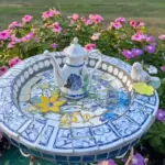 mosiac bird bath with a blue pitcher in the middle in blue and white