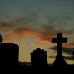 grave markers with a sunset in the background