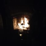 fire in the background with a wine glass relecting in the foreground