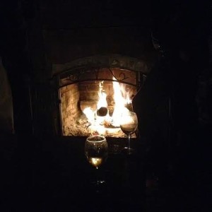 roaring fireplace with two glasses of wine reflecting