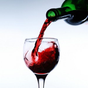 green wie bottle pouring red win into a wine glass