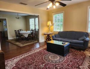 Living room with a black sofa and dining room in background