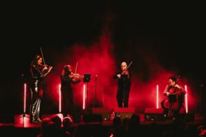 4 musicians playing on a red lighted stage